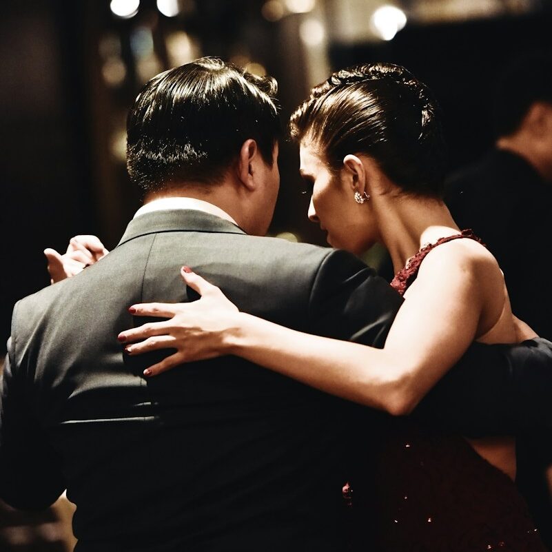 man wearing balck suit jacket and woman wearing red dress dancing